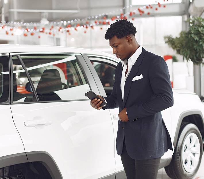 Business man checking phone near a white luxury car